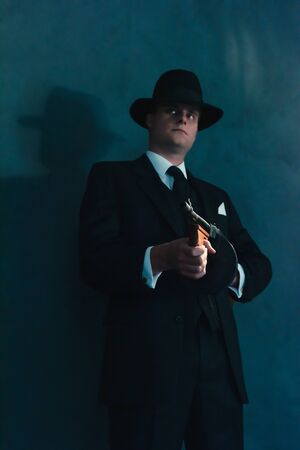 Retro gangster in hat shoots with machine gun.の写真素材