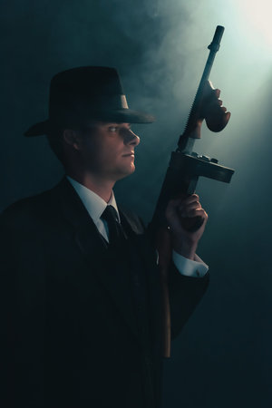 Retro gangster stands with machine gun in mist.