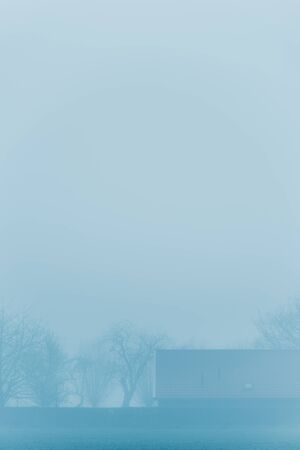 House in foggy countryside during winter.の写真素材