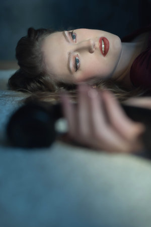 Murdered woman in red dress holding vintage telephone in her hand lying on floor.