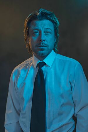 Portrait of a man dressed in a white shirt with black tie under blue and yellow light.の写真素材