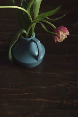 Pink tulips in vintage blue vase on wooden table. Top view.の写真素材