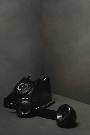Vintage black telephone with receiver next to it in gray empty space.の写真素材