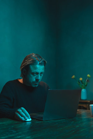 Man working at home behind laptop in the evening.