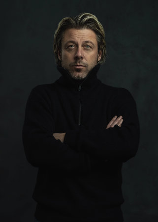 Serious blond man in black woolen sweater.
