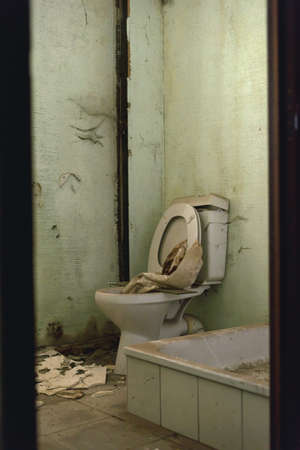 Old dirty broken toilet and shower tray in a dilapidated bathroom.の写真素材