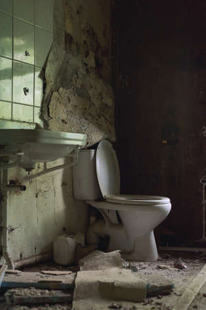 Old dirty broken toilet and sink in a dilapidated bathroom.の写真素材