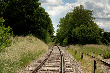Railway in lush countryside in summer under a blue cloudy sky.の写真素材