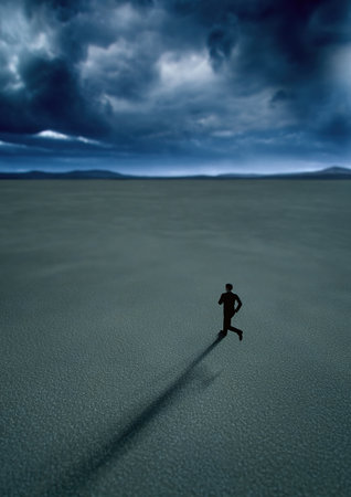 Man in black suit runs in desert with a blue cloudy sky. High angle view. 3D render.の写真素材