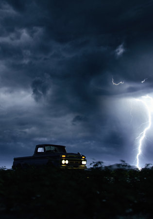 Vintage pickup truck with illuminated headlights in countryside under a dark sky with lightning. 3D render.の写真素材