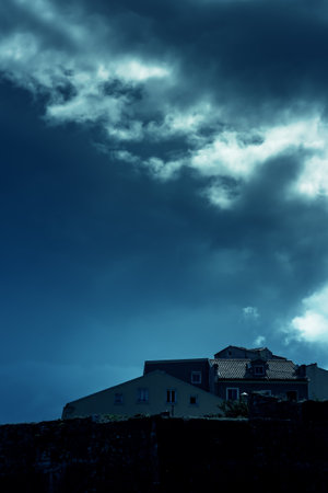 Houses behind a city wall under a dark cloudy sky.の写真素材
