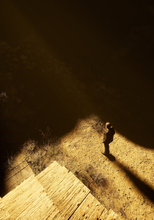 Man stands on sandy soil by a porch in sunlight. High angle view. 3D render.の写真素材