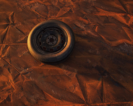 Old car wheel on weathered rusty painted metal sheet.