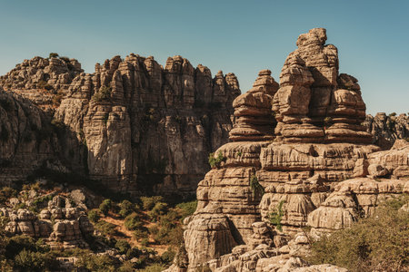 Limestone rock formations like pillars between green vegetation under a blue sky. El Torcal de Antequera National Park. Andalusia. Spain.の写真素材