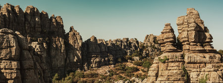 Limestone rock formations like pillars between green vegetation under a blue sky. El Torcal de Antequera National Park. Andalusia. Spain.の写真素材