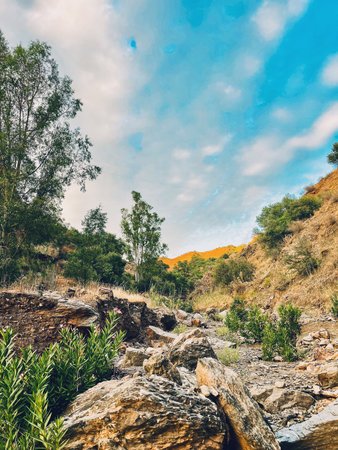 Riverbed in Andalucian rolling landscape under blue sky with some clouds.の写真素材