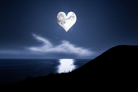 romantic image with a heartshaped moon on a beautiful evening sky with a blue sea belowの写真素材