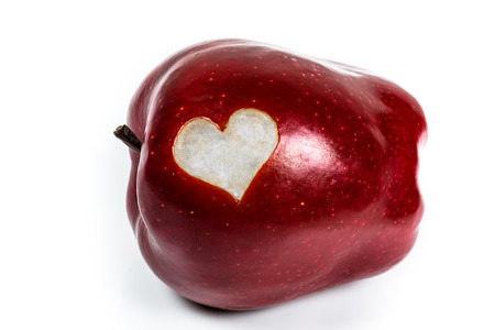 Red Delicious apple with a cutout heart on a white backgroundの写真素材