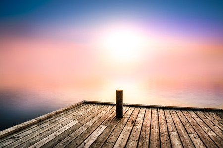peaceful and mysterious picture with morning light over a lake with a bridge in the foregroundの写真素材