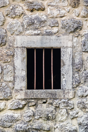 barred prison window with stone walls aroundの写真素材
