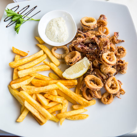 calamares and french fries with mayonnaise on a white plateの写真素材