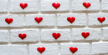 lots of little hearts on a white brick wall backgroundの写真素材