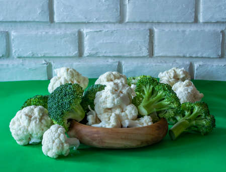 inflorescences of cauliflower and broccoli on a wooden plate,brick backgroundの写真素材