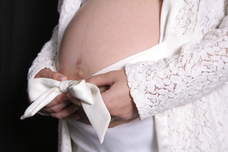 Closeup of pregnant woman's belly with white bowの写真素材