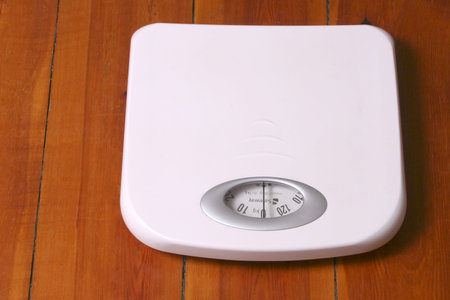 White bathroom scale placed on wood floor