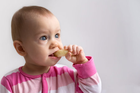adorable baby girl  eating  a crunchy corn snackの写真素材