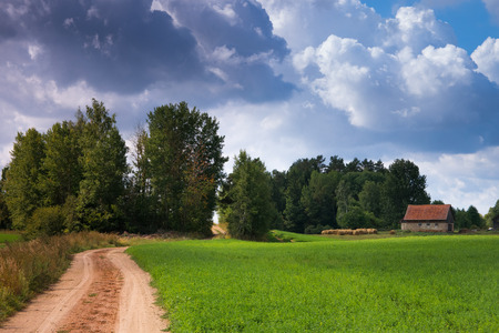 Summer countryside landscape. Twisting road between meadows and barn.の写真素材