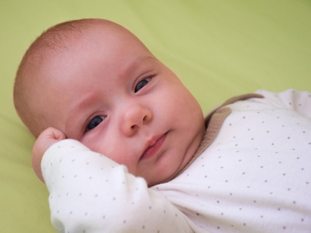 Three-month old smiling baby-girl carefully observes the world.の写真素材