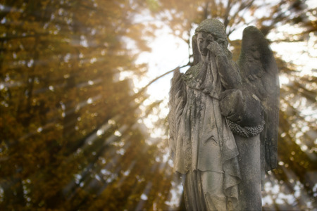 Crying angel statue at old cemetery in autumn. Double exposure.の写真素材