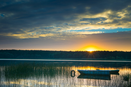 Rowing boats floating over the Lake Lasmiady  waters. The sun rises just behind them. Masuria, Poland.の写真素材