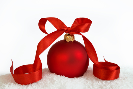 Christmas ball with red ribbon on artificial snow flakes.の写真素材