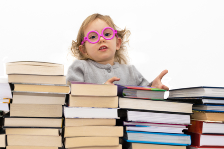 Three year old girl in pink glasses gives the book. Isolated on white.の写真素材
