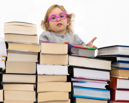 Three year old girl in pink glasses gives the book. Isolated on white.の写真素材