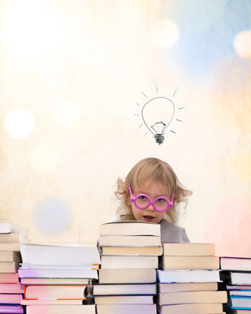 Three year old girl in pink glasses got an idea. Paper, colorful background.の写真素材