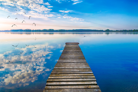 EBirds fly over empty footbridge. The lake Selment Wielki, Masuria, Poland.の写真素材
