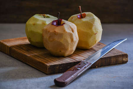 Three peeled apples on a cutting board in the kitchen.の写真素材