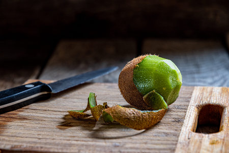 Kiwi fruit on a cutting board and knife on wooden background