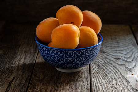 Ripe apricots in a bowl on a wooden background.の写真素材