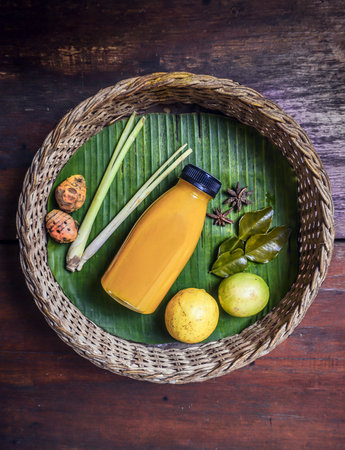 A glass of herbal drink with lemongrass, turmeric and star anise on rattan basket with banana leaf...