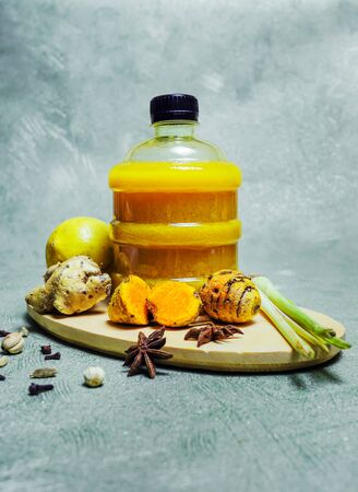 A bottle of herbal drink with lemongrass, turmeric, clove and star anise on wooden place matの写真素材