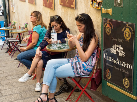 Ajaccio, Corsica France: August 17, 2017, Women sitting on the street watching their phones in the historic center of Ajaccioのeditorial素材