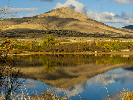 Sunny mountain with clouds reflected in the water of a lake の写真素材