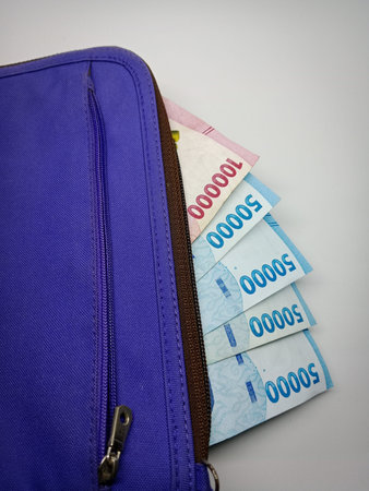Money in a blue leather bag on a white background. Indonesian Rupiah
