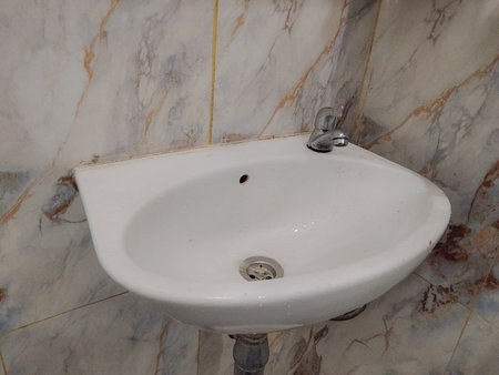 White washbasin in a bathroom with marble tiles. Bathroom interior