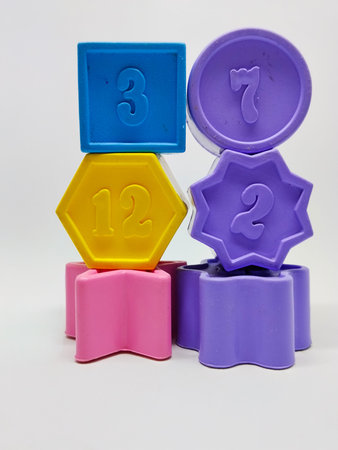 Colorful plastic geometric shape with numbers on white background. Number 3, 7, 12, and 2