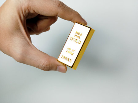 Hand holding gold bars on white background, closeup